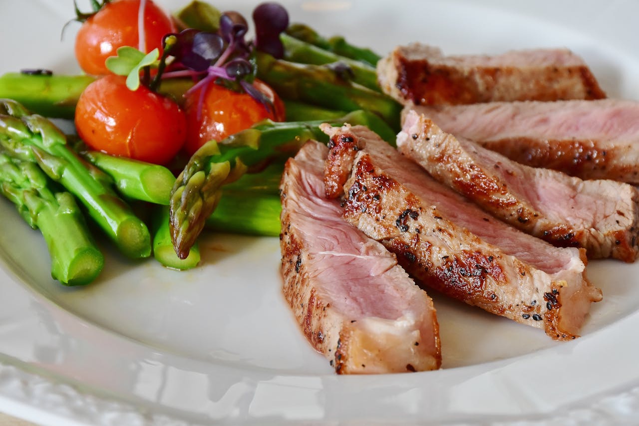 about-02 Close-up of grilled steak slices with asparagus and cherry tomatoes, perfect for a healthy meal.